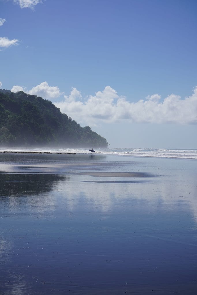 A lone surfer on a beach near Pavones, Costa Rica